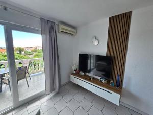 a living room with a flat screen tv and a balcony at Apartmani Janja in Krk