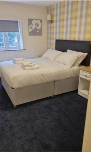 a bedroom with a large bed with white sheets and a window at The Aston Inn in Birmingham