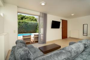 a living room with a couch and a large window at The peaceful escape with shared pool in Porto Rafti