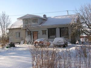 a house with two cars parked in the snow at Majatalo Tyrni in Nakkila