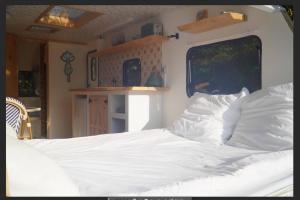 ein Schlafzimmer mit einem Bett mit weißer Bettwäsche und einem Fenster in der Unterkunft Cherry Tree Caravan in Podentes + 50 Fotos