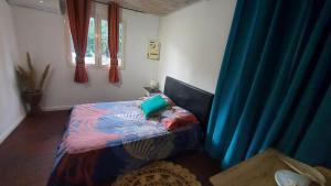 a bedroom with a bed with a blue curtain at Maison élégante à Saint-Pierre + Piscine in Casabona +8 photos