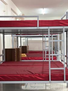 a bedroom with two bunk beds with red sheets at DM Bliss in Chikmagalūr