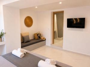 a room with a bed and a television and towels at Pattys Desing Suites- Private Hot Tub with yard- Fira Center in Firostefani