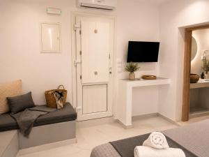 a living room with a couch and a tv at Pattys Desing Suites- Private Hot Tub with yard- Fira Center in Firostefani +15 photos