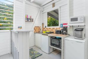 a white kitchen with a counter and a microwave at Appartement charmant au Carbet avec vue sur la mer - 50 m² in Le Carbet