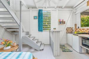 a kitchen with white walls and a spiral staircase at Appartement charmant au Carbet avec vue sur la mer - 50 m² in Le Carbet +12 photos