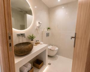 a bathroom with a sink and a toilet and a mirror at Pattys Desing Suites- Private Hot Tub with yard- Fira Center in Firostefani