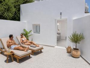 two people sitting in chairs on the patio of a house at Pattys Desing Suites- Private Hot Tub with yard- Fira Center in Firostefani
