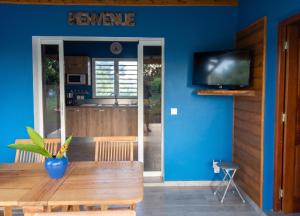 a dining room with a wooden table and a blue wall at Villa charmante au Moule avec piscine in Le Moule