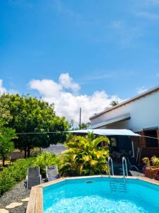 a pool with chairs and an umbrella next to a house at Villa charmante au Moule avec piscine in Le Moule +7 photos