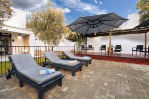 a patio with two chairs and an umbrella at Karoo Retreat- Self Catering Villas and Guest House in Oudtshoorn