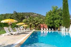 a swimming pool with lounge chairs and umbrellas at Olympos Donkisot Pansiyon in Antalya
