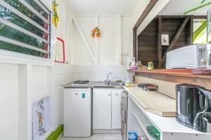 a white kitchen with a sink and a stove at Bungalow charmant à Rivière-Salée avec terrasse privée in Rivière-Salée
