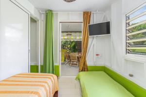 a bedroom with green curtains and a bed and a window at Bungalow charmant à Rivière-Salée avec terrasse privée in Rivière-Salée