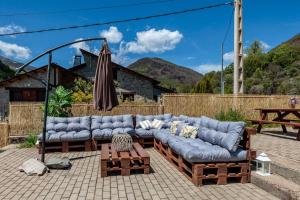 a patio with two couches and an umbrella at La Casona de Omaña in Fasgar