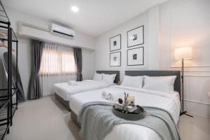 a white bedroom with two beds and a table at Arun Sa Wad - Chinatown House in Bangkok