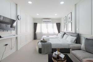 a white bedroom with a bed and a couch at Arun Sa Wad - Chinatown House in Bangkok