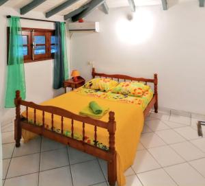 a bedroom with a bed with a yellow comforter at Appartement spacieux à Deshaies avec vue sur mer in Deshaies +5 photos