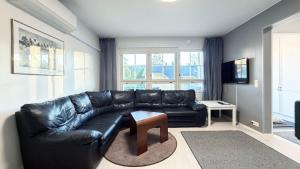 a black leather couch in a living room with a table at Apartamento la Casa Tahko in Kuopio