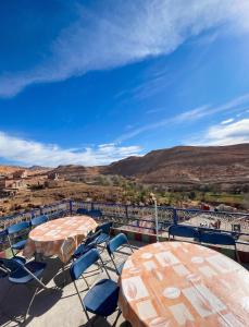 two tables and chairs on a patio with mountains at Sumptuous Villa in Aït Ben Haddou with Private Pool in Aït Benhaddou