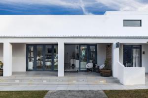 a white house with glass doors and a patio at Karoo Retreat- Self Catering Villas and Guest House in Oudtshoorn +77 photos
