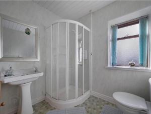 a white bathroom with a shower and a sink at ANNORA Bar & Accommodation in Portnoo