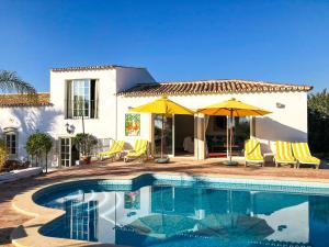 a swimming pool with chairs and umbrellas in front of a house at Elegant villa with sea view in Loulé + private pool in Loulé