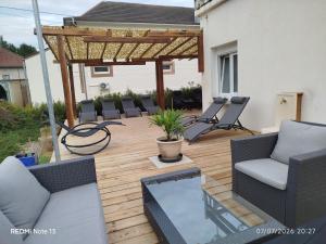 a wooden deck with chairs and a pergola at Gîte "fils de laine" Piscine chauffée interieure et Sauna ouverts toute l'année in Celles-sur-Plaine