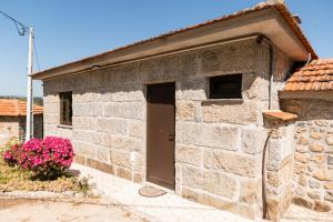 a stone building with a door and a plant with pink flowers at Idyllic Villa in Fornos + Pool! in Fornos