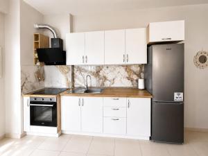 a kitchen with white cabinets and a stainless steel refrigerator at Sole Mare - Beach House in Kavajë