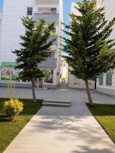 two trees on a sidewalk in front of a building at Sole Mare - Beach House in Kavajë