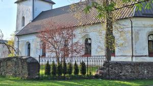 an old white church with a fence in front of it at Petite Haven in Grobiņa