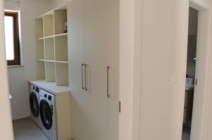 a laundry room with white cabinets and a washer and dryer at Villa GB in Brtonigla