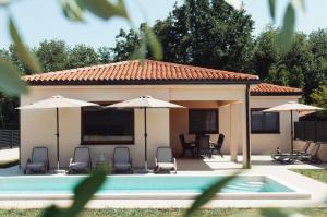a house with a pool and chairs and umbrellas at Villa GB in Brtonigla