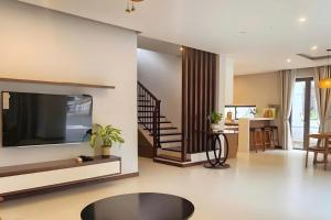 a living room with a flat screen tv and a staircase at Nova Villas Phu Quoc in Phú Quốc