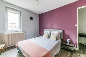 a bedroom with a purple wall and a bed with pillows at Maison conviviale à Bourbon-Lancy avec équipements modernes in Bourbon-Lancy