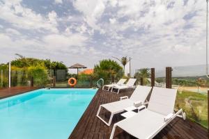 a pool with white lounge chairs and a swimming pool at Penedo Escape Sea Suites in Colares
