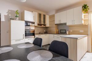 a kitchen with white cabinets and a table and chairs at Ferienwohnung Leibnitz Südsteiermark in Leibnitz