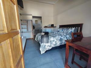 a bedroom with a bed and a table and a refrigerator at The Lantern Porch Guesthouse in Vryburg