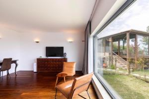 a living room with a large window and a television at Penedo Escape Sea Suites in Colares