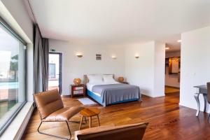 a bedroom with a bed and a couch and a chair at Penedo Escape Sea Suites in Colares +61 photos