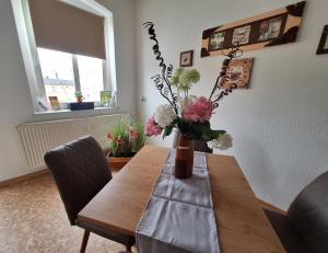 a dining room table with a vase of flowers on it at Ferienwohnung MIWE Gesundheitszent in Forst