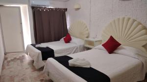 a hotel room with two beds with red pillows at CH Paradise Condesa in Acapulco