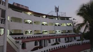 a large white building with balconies and a palm tree at CH Paradise Condesa in Acapulco