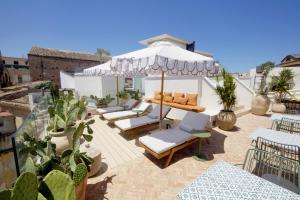 a patio with chairs and an umbrella and some plants at Casa Nostra Luxury Suites & Spa in Palermo