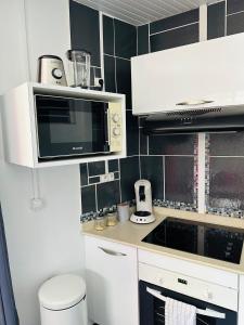 a kitchen with a microwave and a stove top oven at Appartement charmant à Sainte-Rose, 60m² + piscine in Sainte-Rose