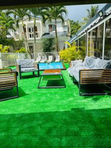 a yard with green grass and benches and a pool at Appartement charmant à Sainte-Rose, 60m² + piscine in Sainte-Rose