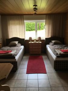 two beds in a room with a red rug at Ferienhaus Haber in Schluchsee