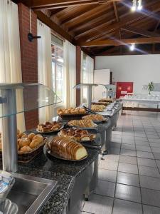 a row of buffet tables with bread and pastries at FECEP Pousada - 5 minutos a pé da praia in Guaratuba